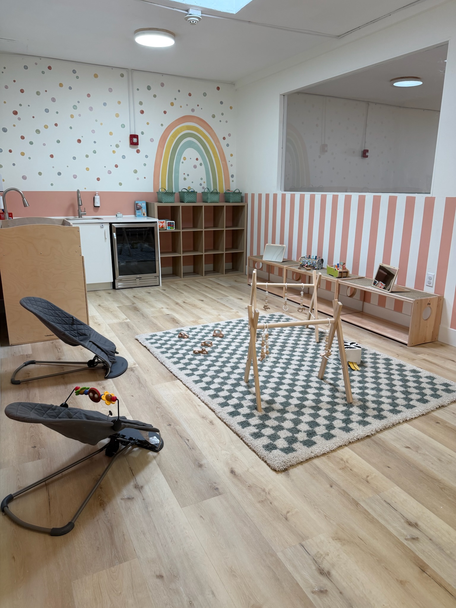 Happy Nook infant room with rainbow mural and play space