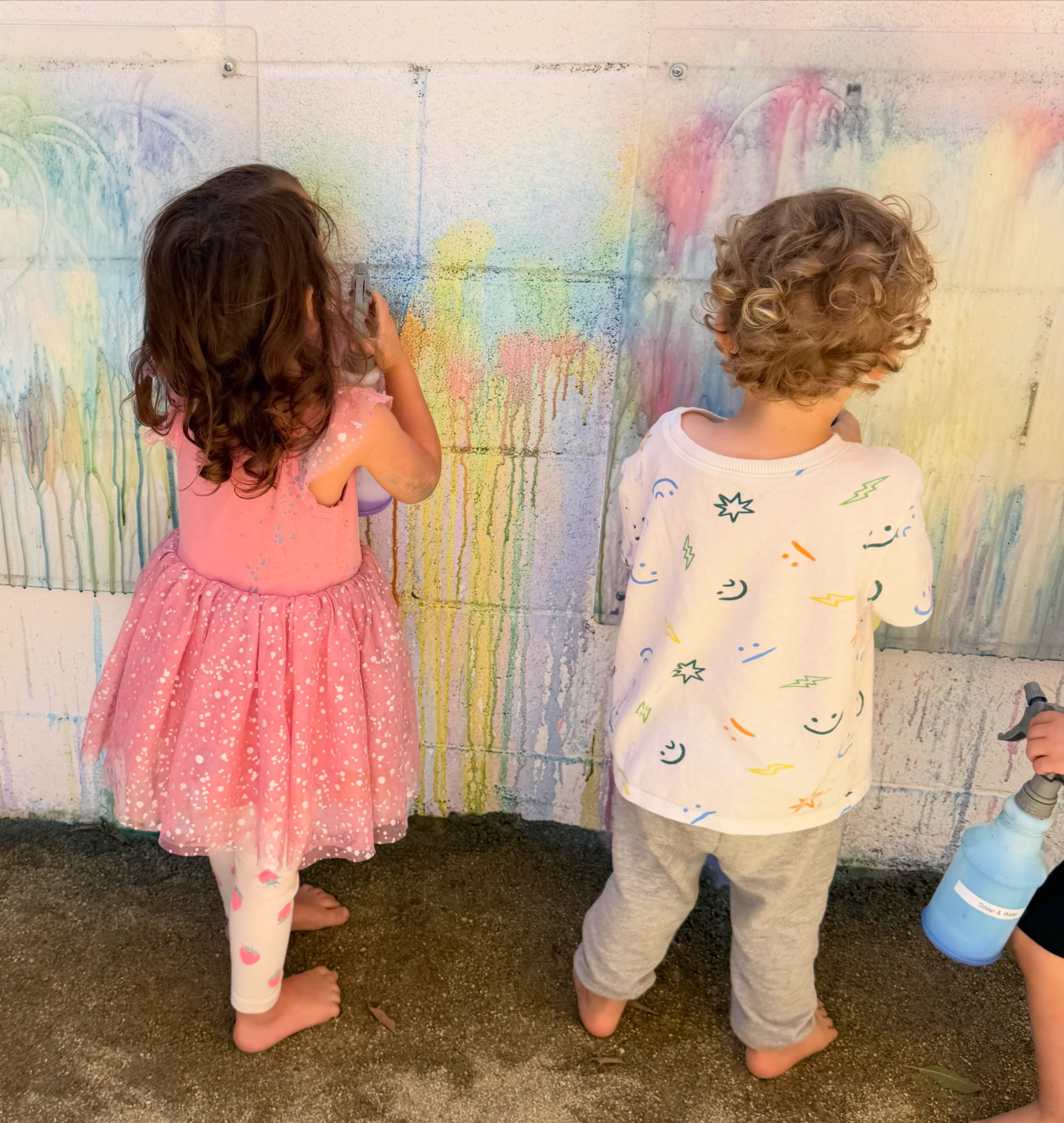 Two children painting with chalk on the outdoor wall at Happy Nook Los Angeles
